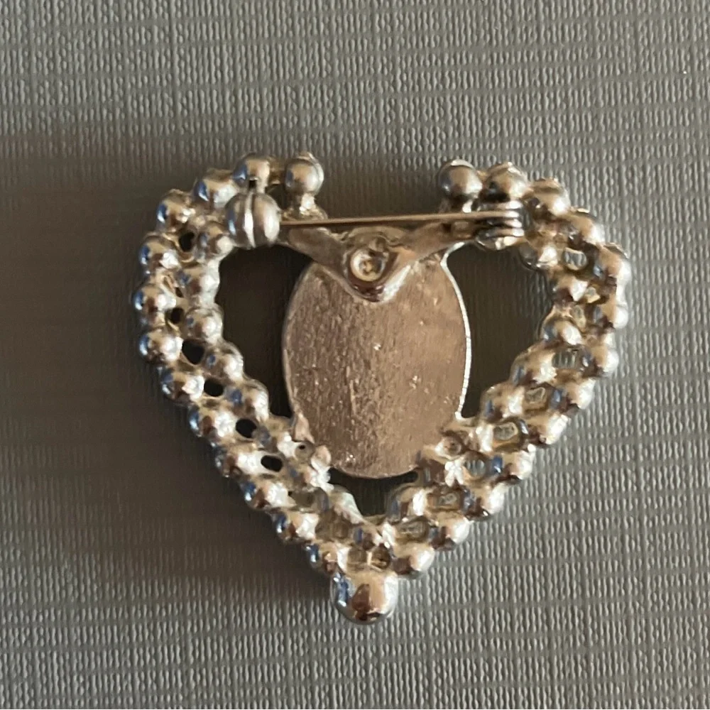 Vintage heart-shaped brooch featuring a black and white cameo with faux pearls.